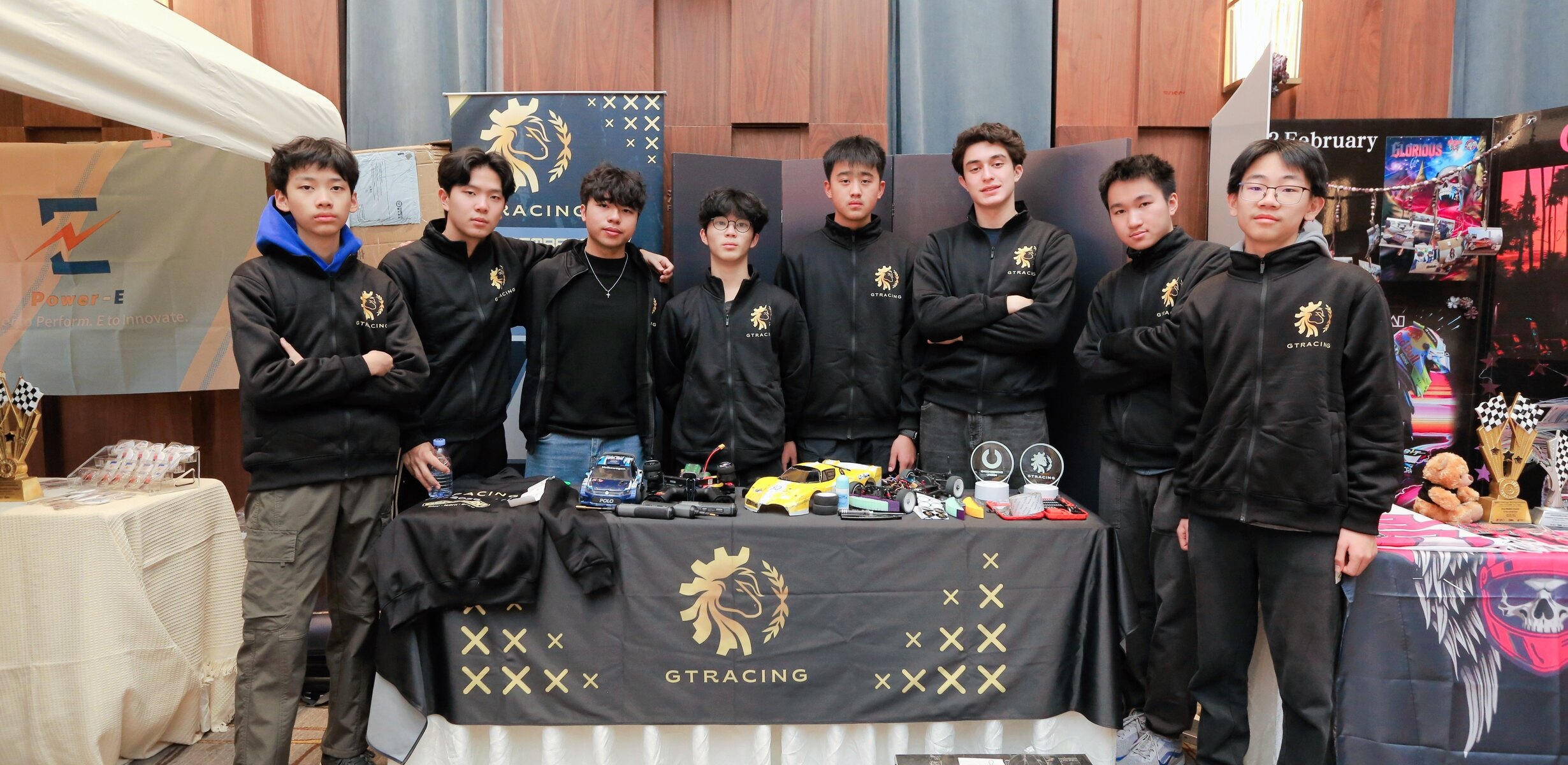 GT Racing members standing behind a display of cars, prototypes, tools, and awards