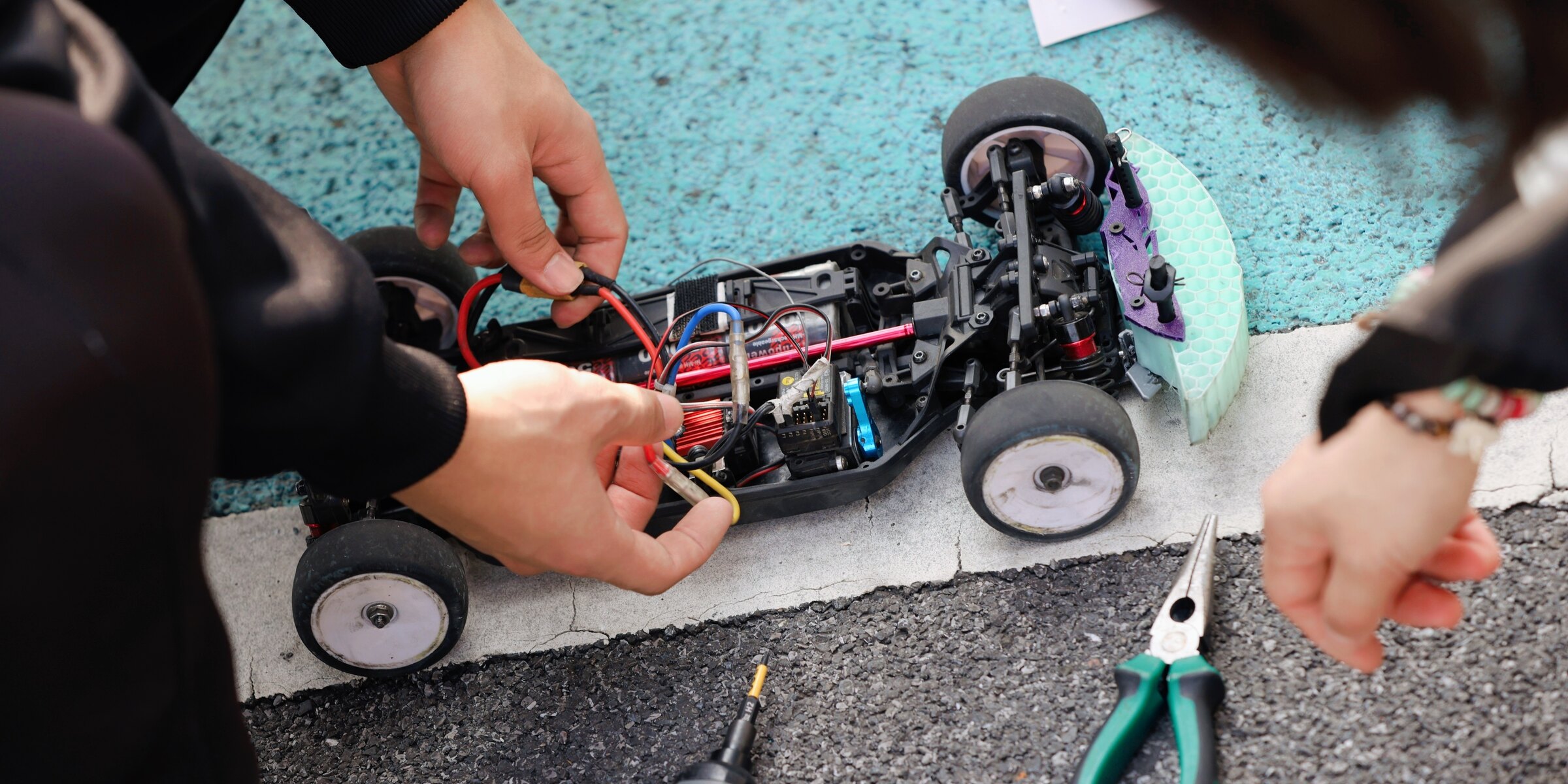 Several GT Racing members working together on an open race chassis at trackside