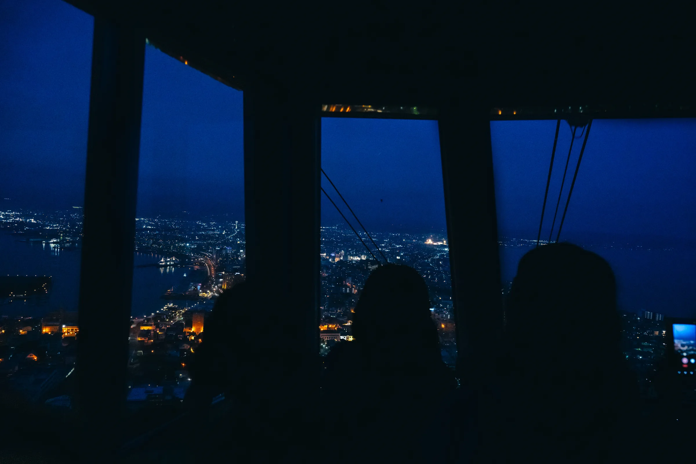 Passengers silhouetted inside the Mount Hakodate Ropeway against the blue city below