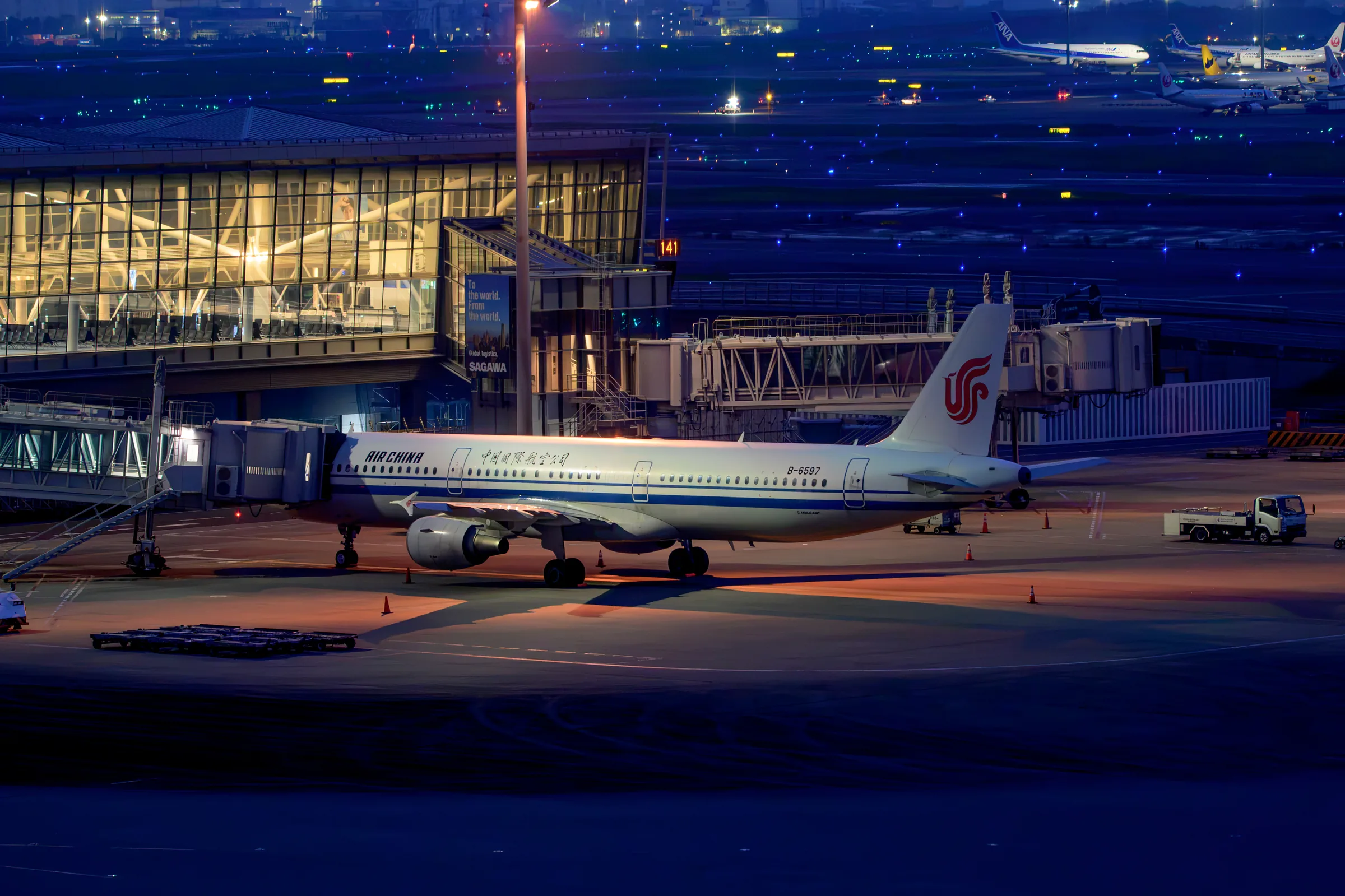 An Air China aircraft at a gate surrounded by blue taxiway lights before dawn