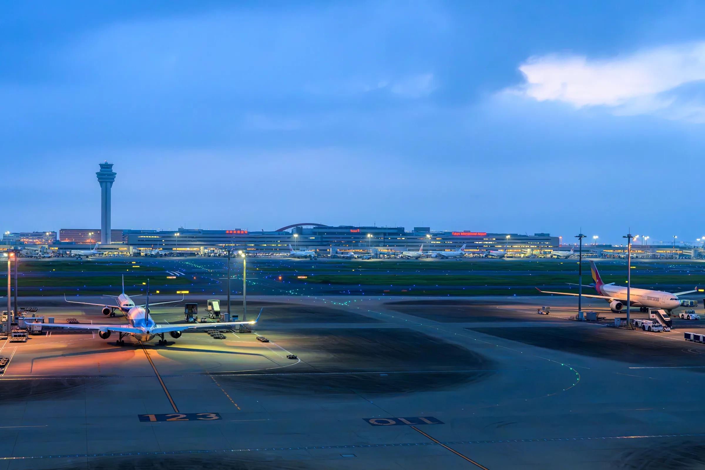 A wide view across Haneda Airport toward the control tower in blue-hour light