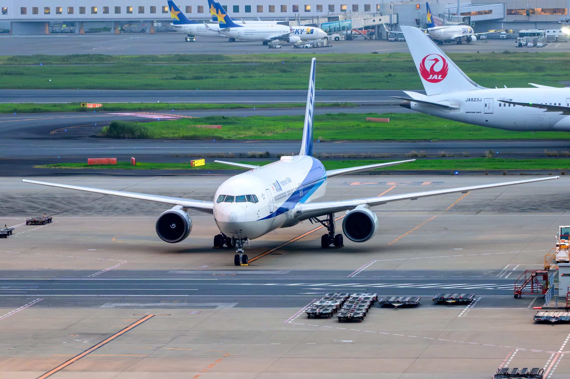 An ANA aircraft turning toward the camera on the apron