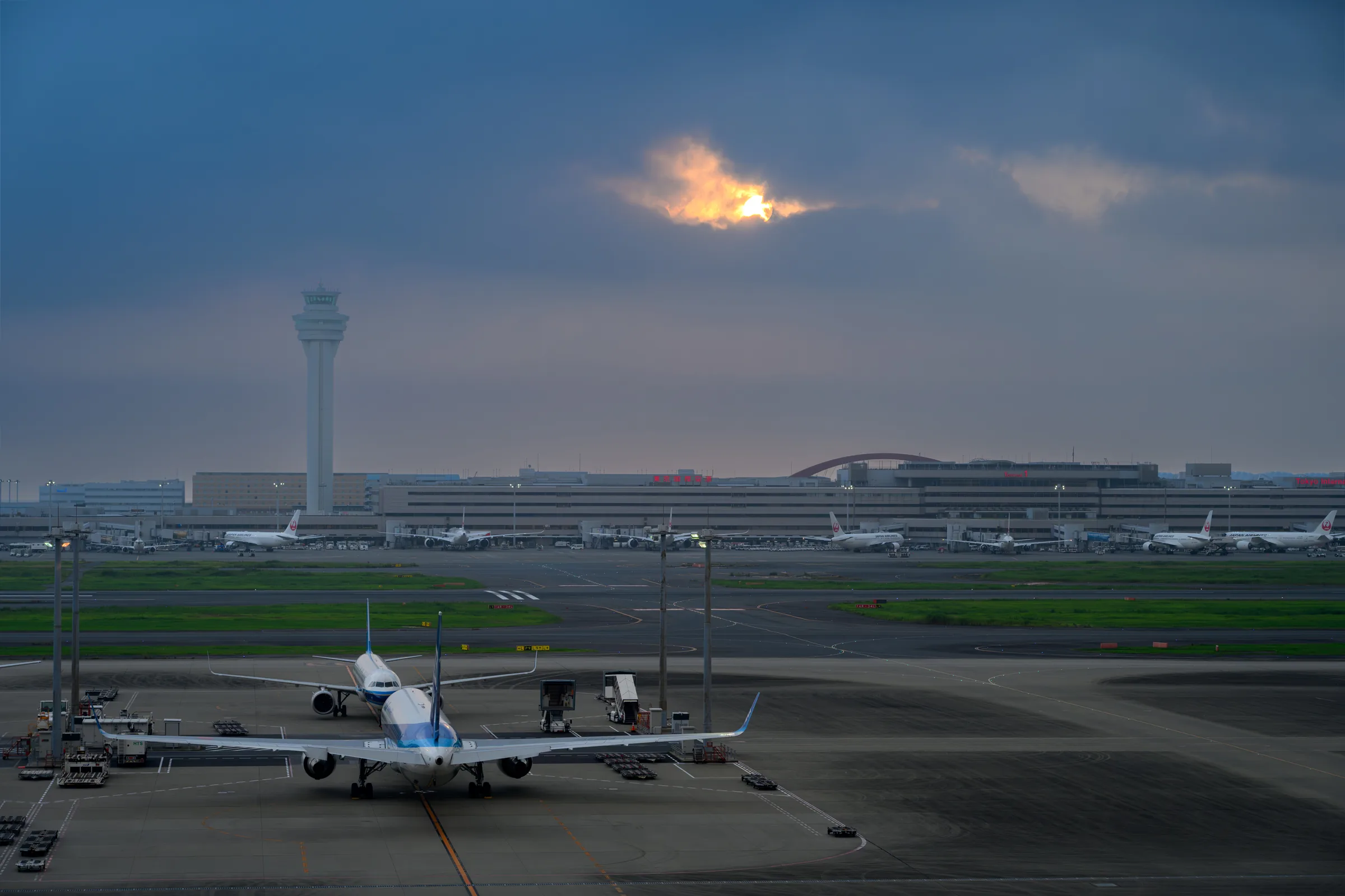 The rising sun breaking through cloud above Haneda Airport and its control tower