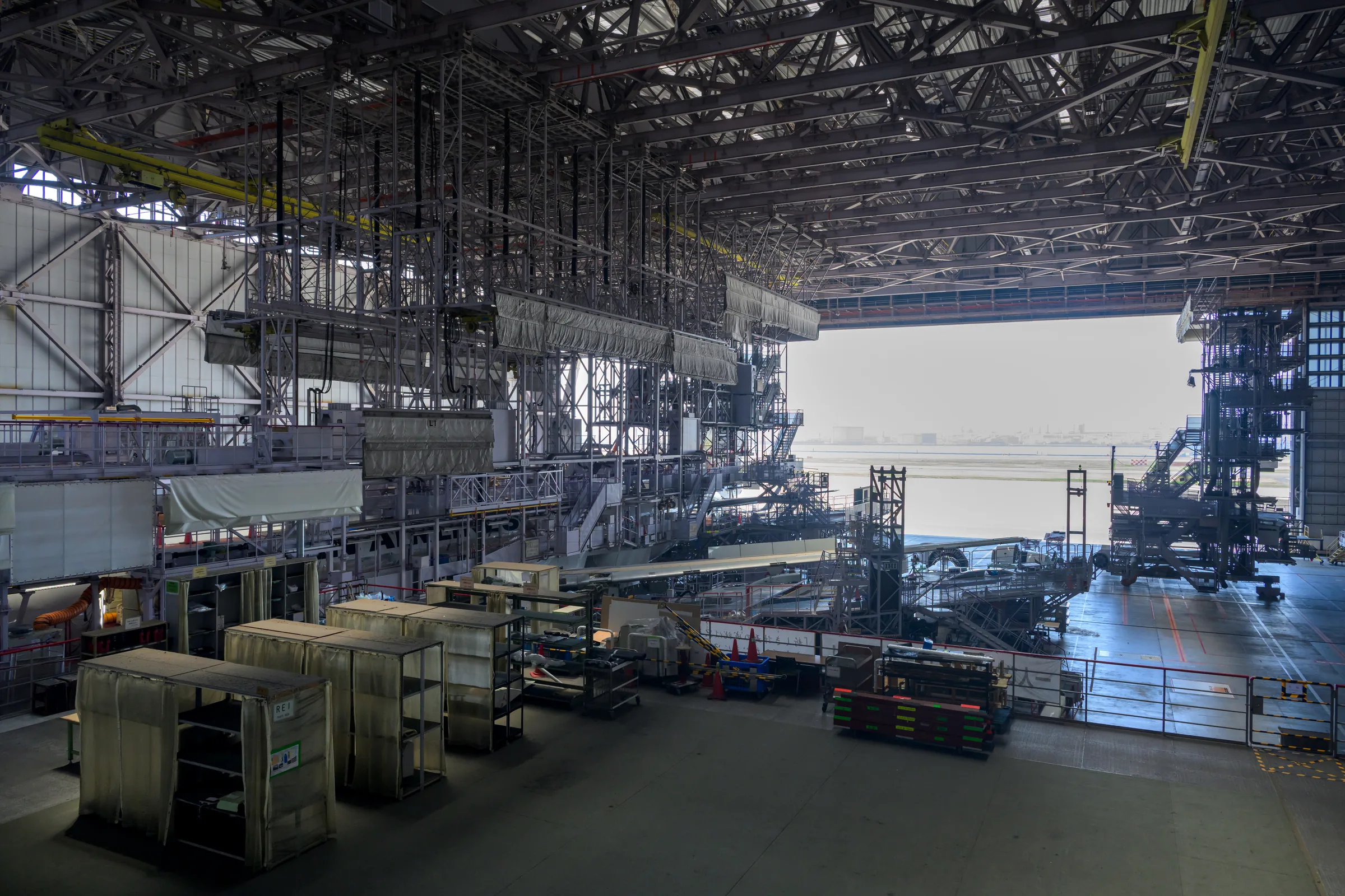 Maintenance structures filling a vast aircraft hangar open to the runway
