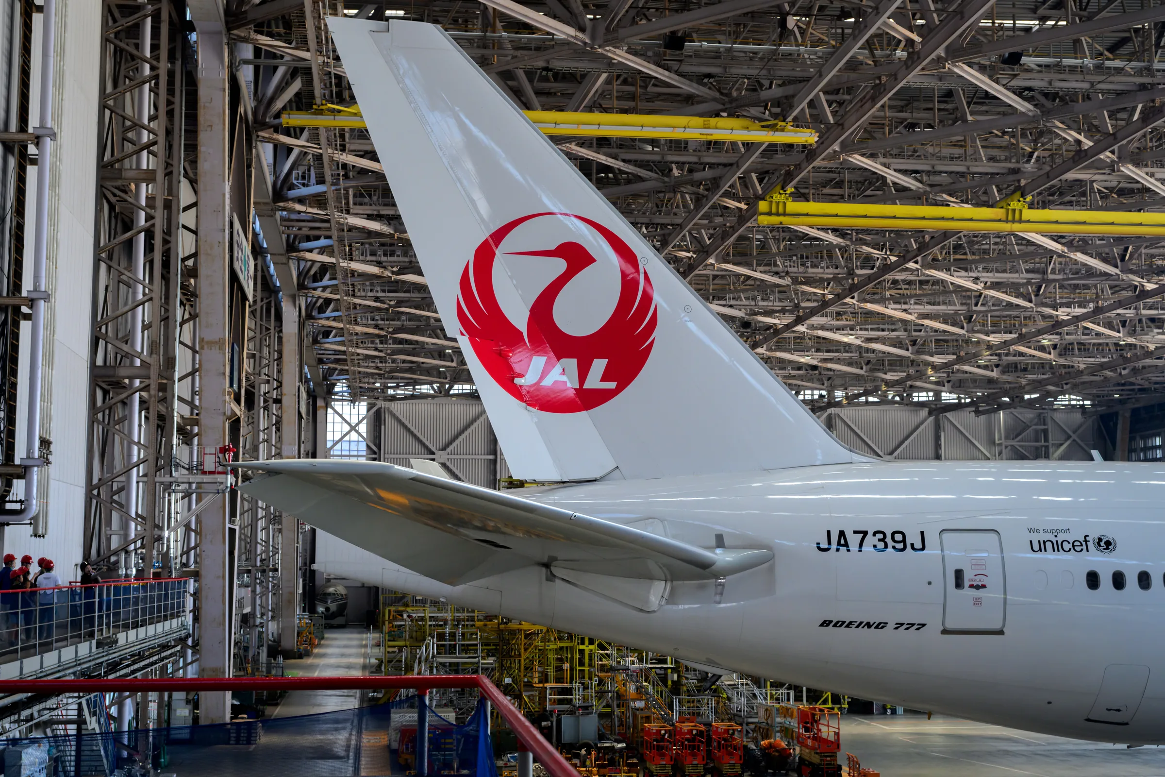 The red Japan Airlines tail visible among maintenance gantries