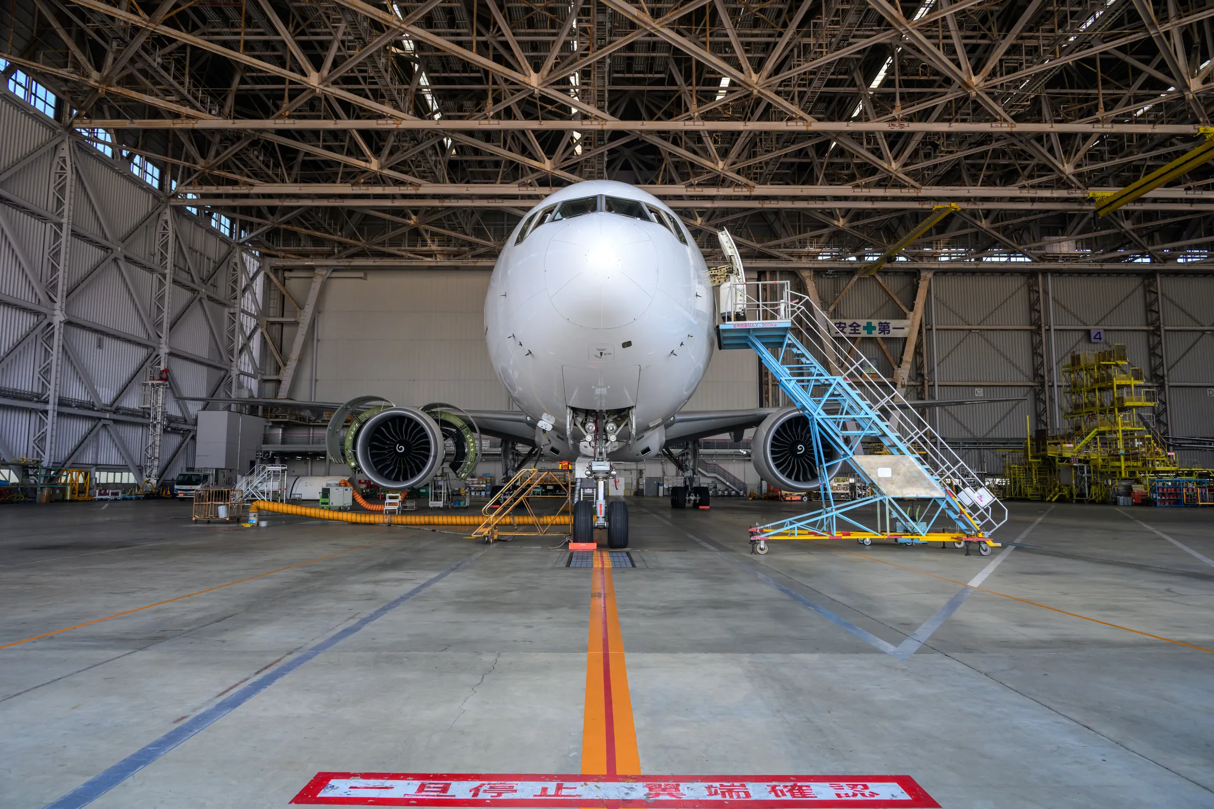 A widebody aircraft seen directly from the front inside a maintenance bay