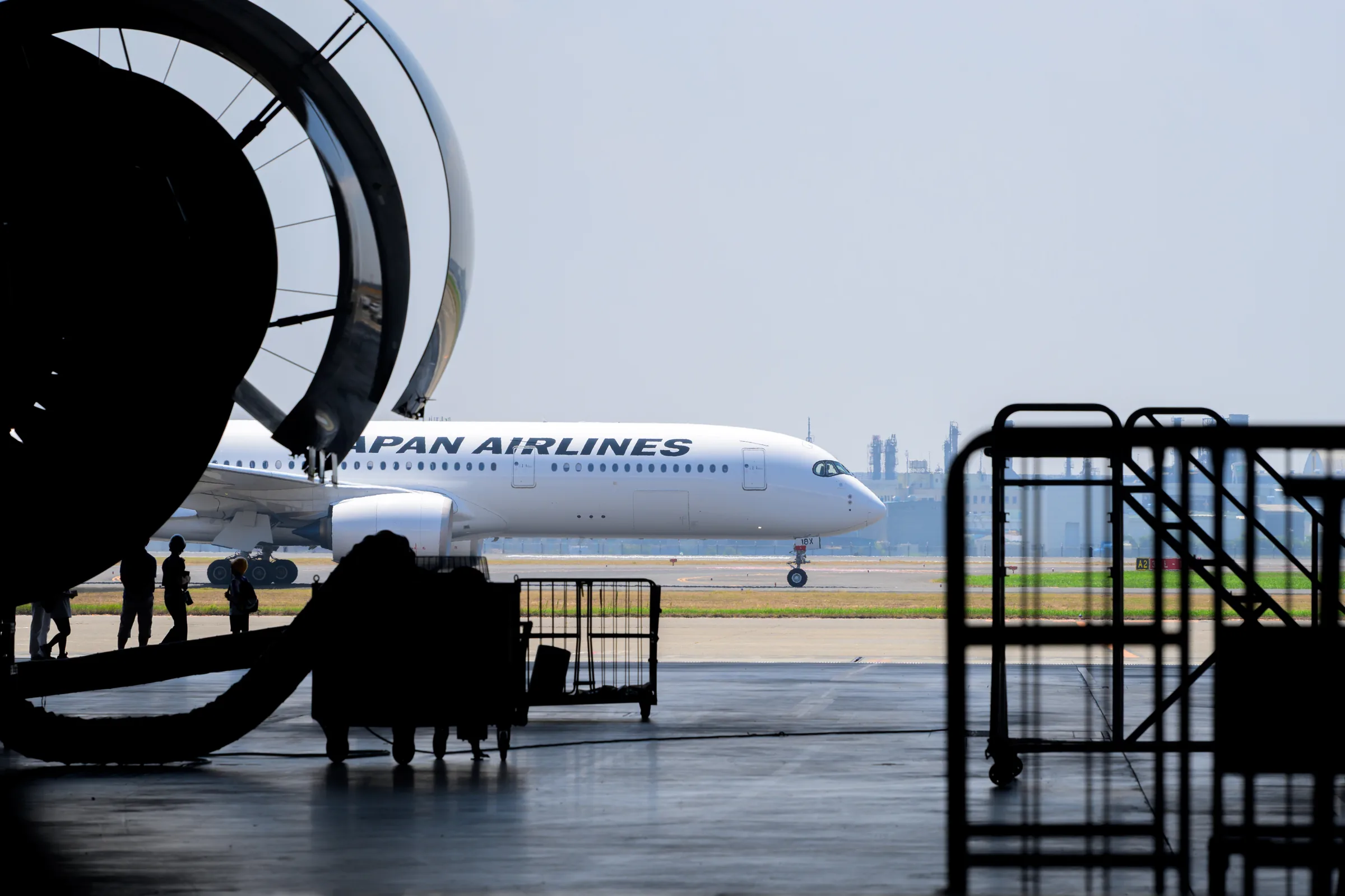 An aircraft outside the hangar framed by an opened engine cowling and maintenance carts