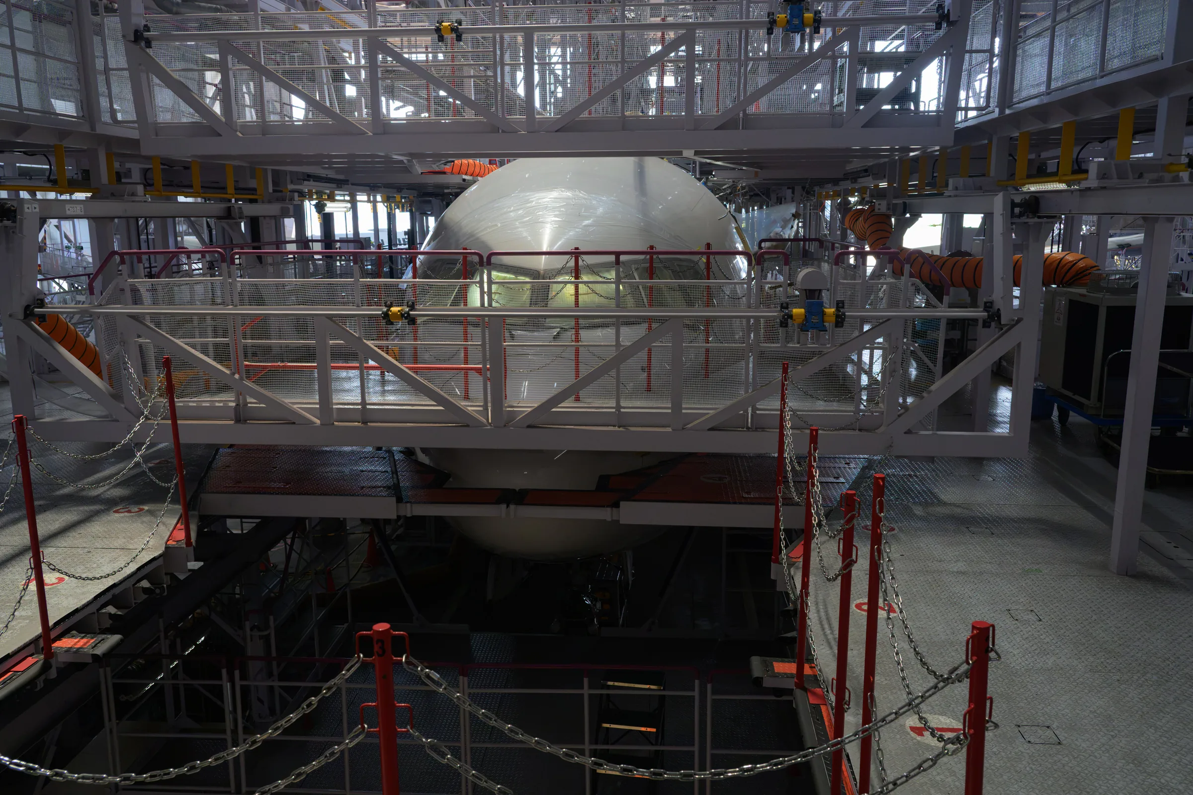 A large aircraft nose surrounded by maintenance stairs and access structures