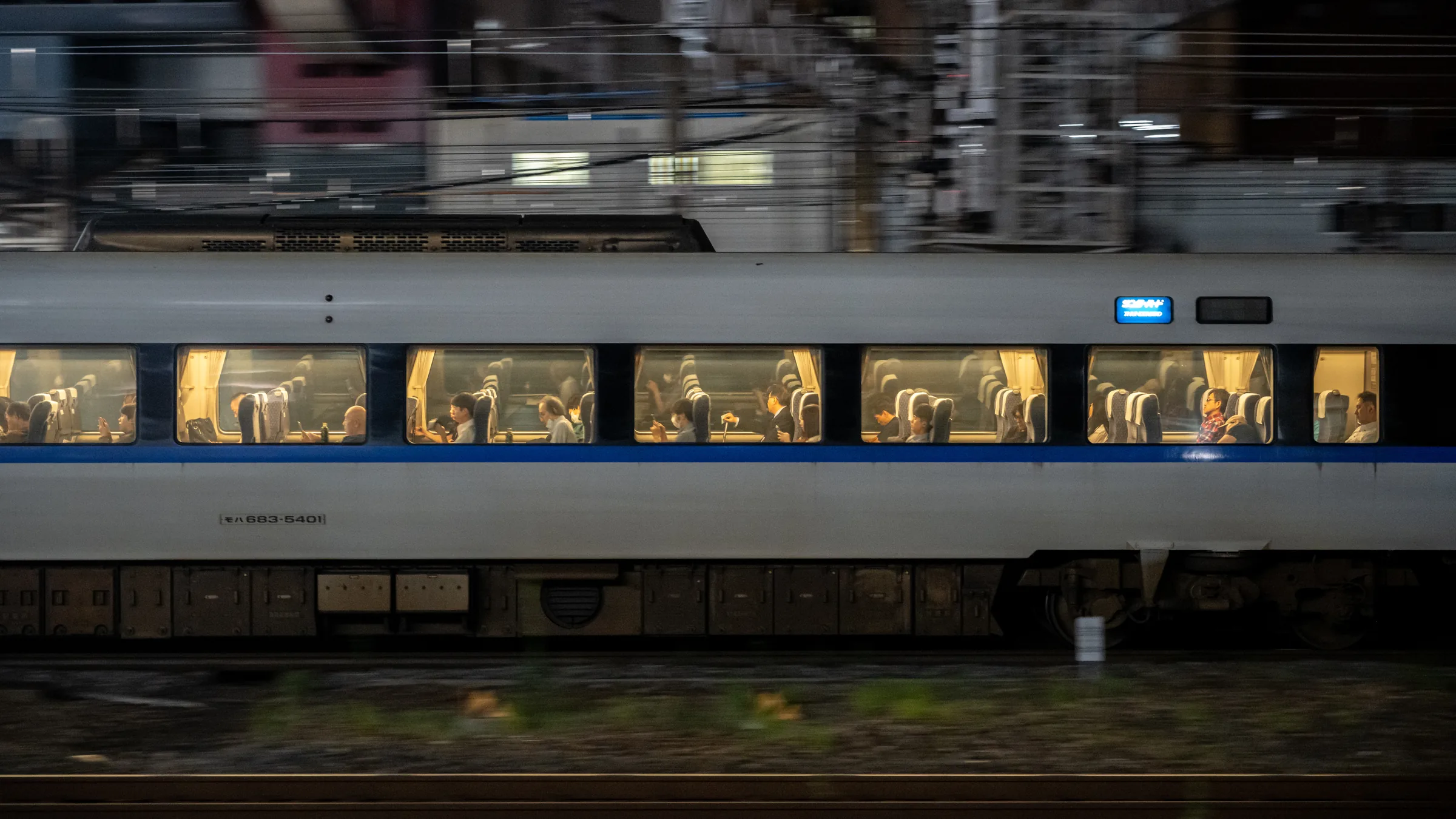 A passenger train streaking past with illuminated windows and seated riders