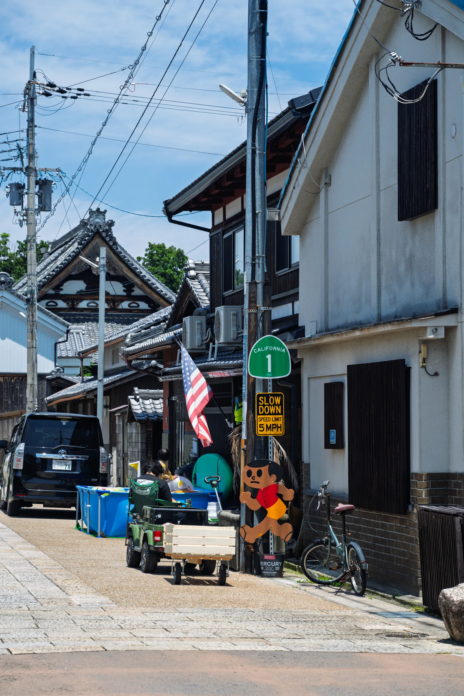 A narrow lakeside town street with bicycles, shopfronts, and people in the afternoon sun