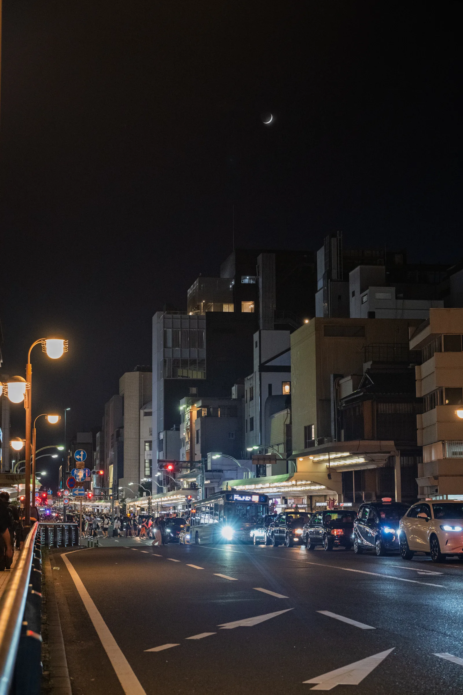 A broad Kyoto road glowing with headlights beneath the night sky