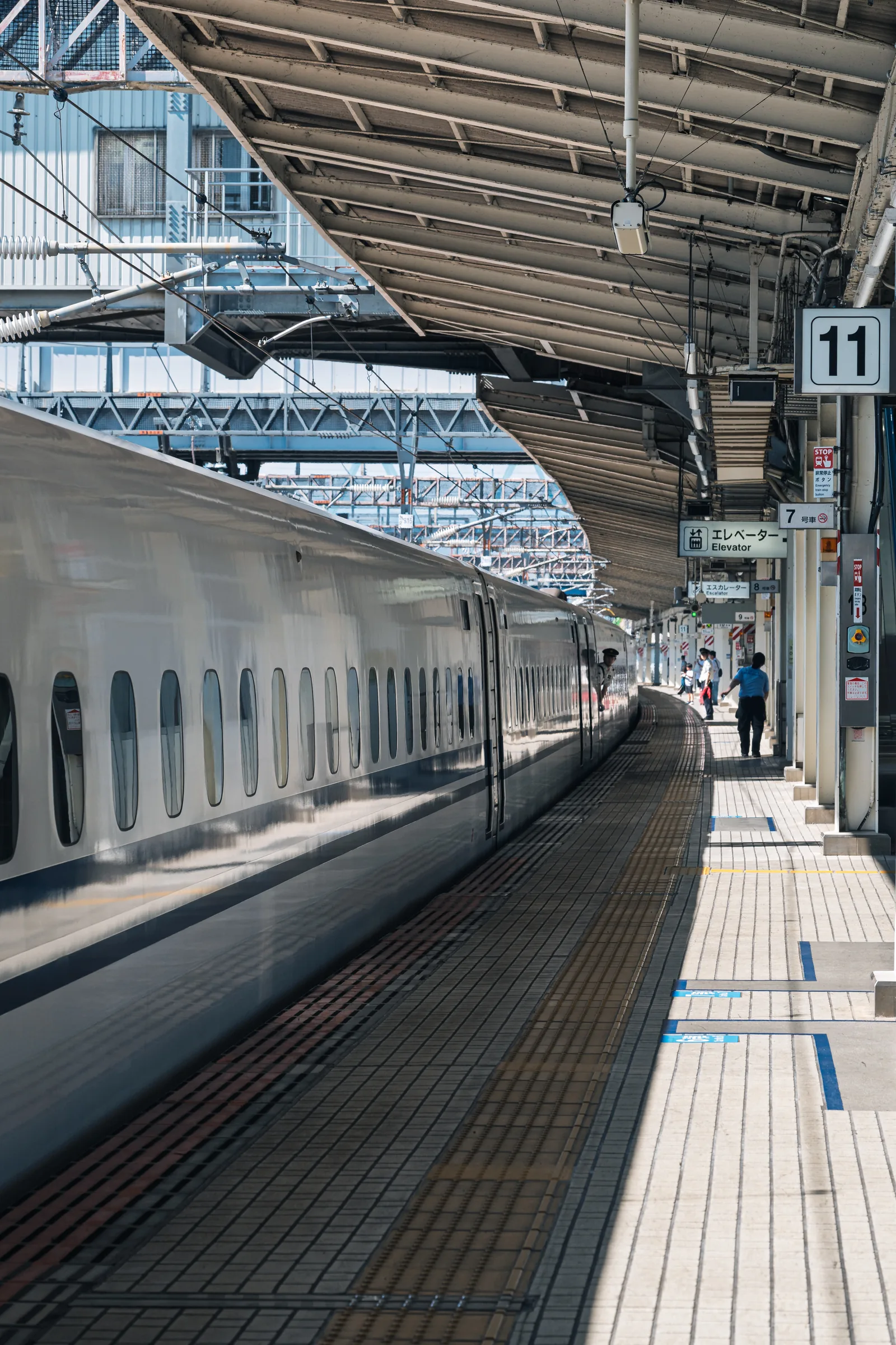 A white Shinkansen stretching along platform eleven beneath a steel station roof