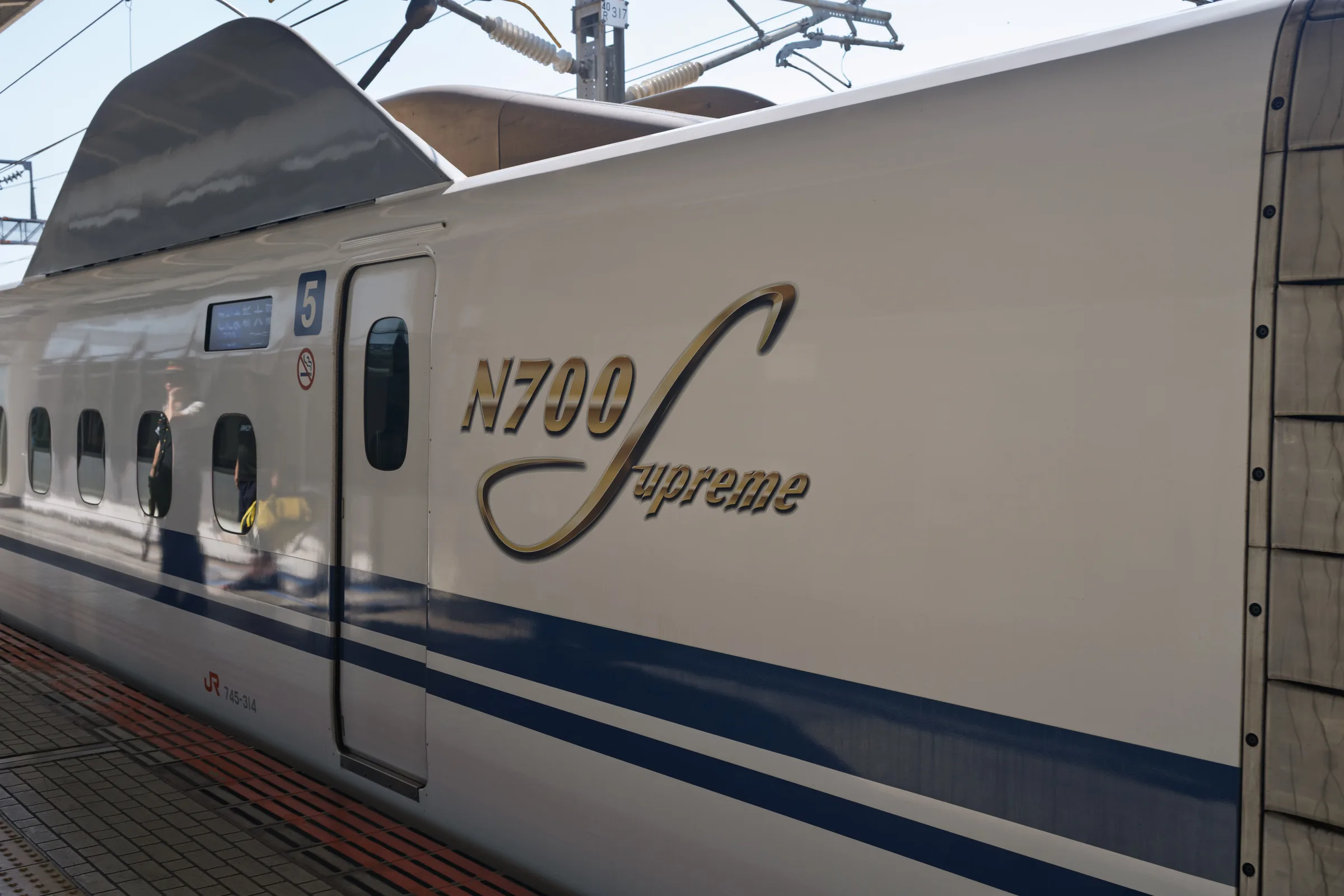 The gold N700S Supreme emblem painted along the side of a Shinkansen carriage