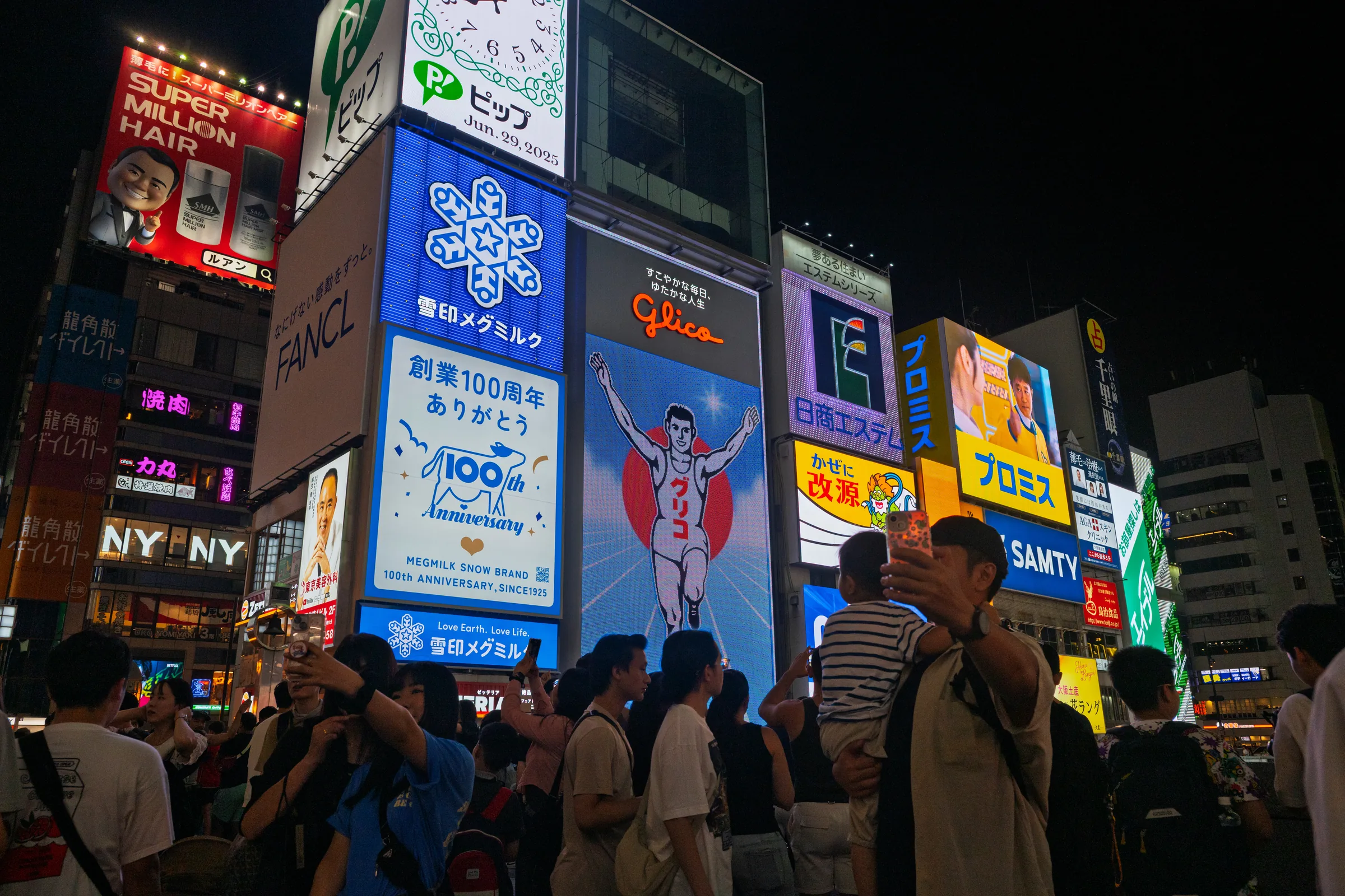 A crowd photographing the illuminated Glico sign in Dotonbori at night