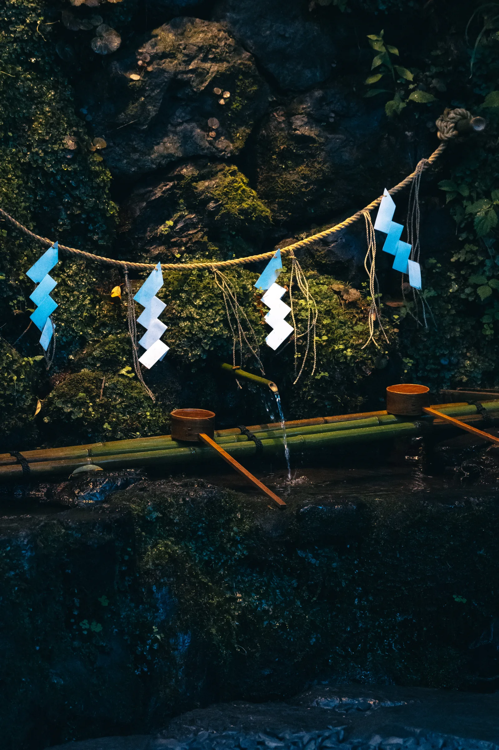 Sacred spring water pouring into a stone basin beneath paper streamers