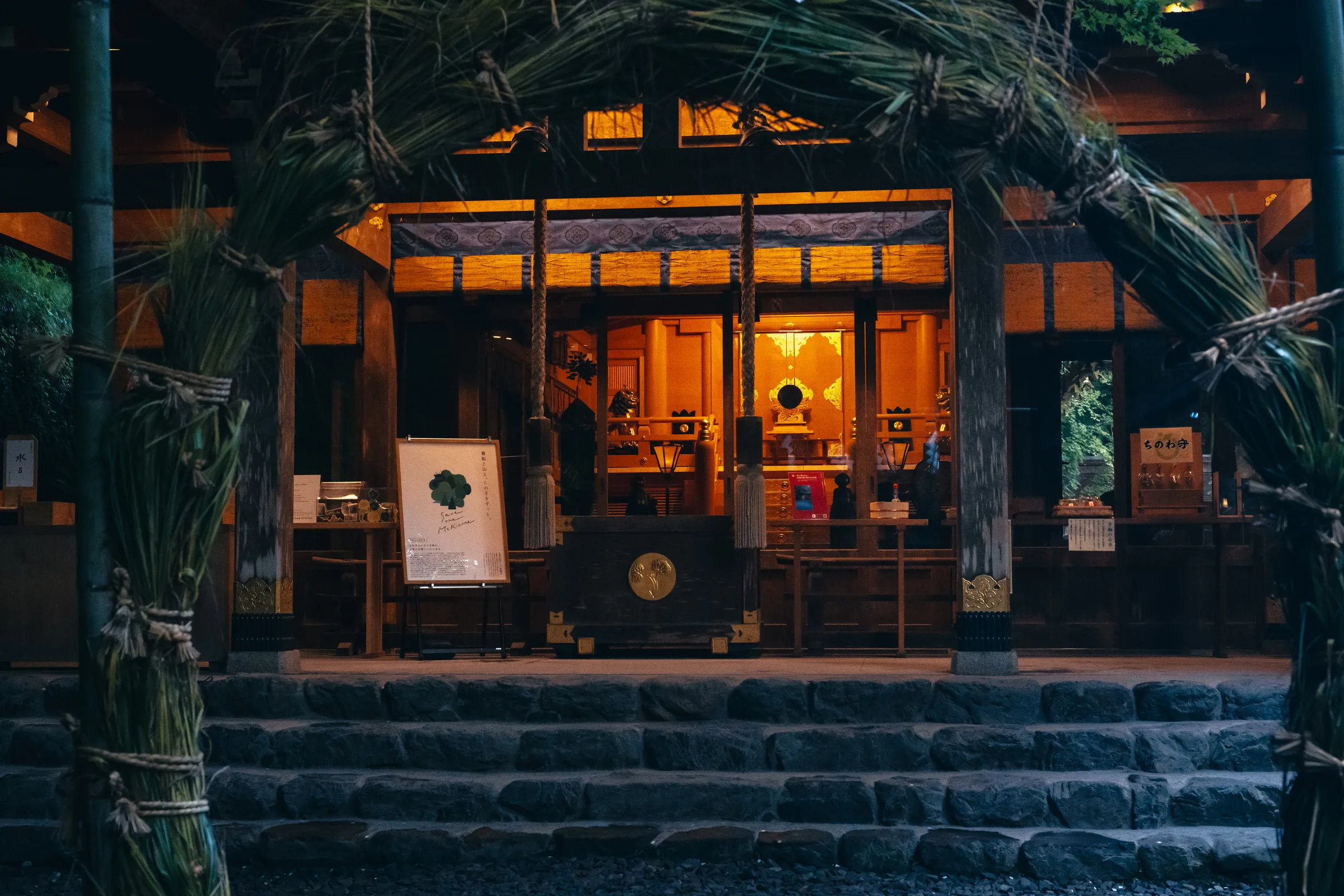 The softly illuminated inner shrine seen through a large woven grass ring at dusk
