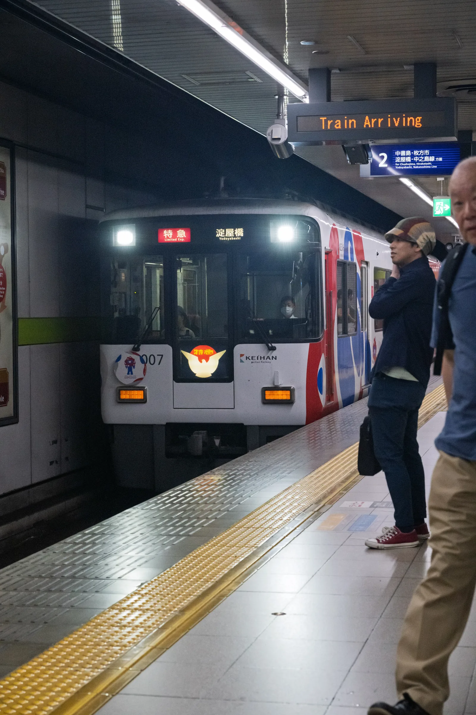 A dark commuter train waiting at an underground platform as passengers board