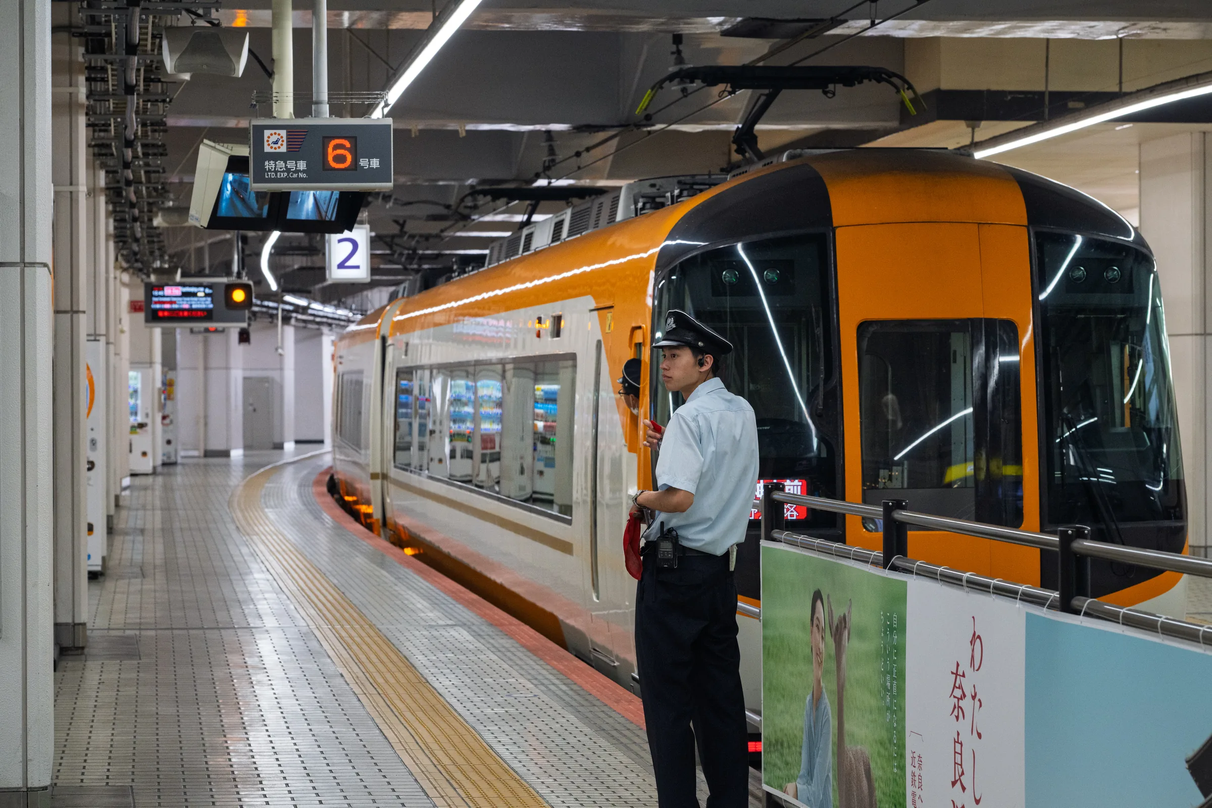 An orange Kintetsu limited express standing beneath the station lights