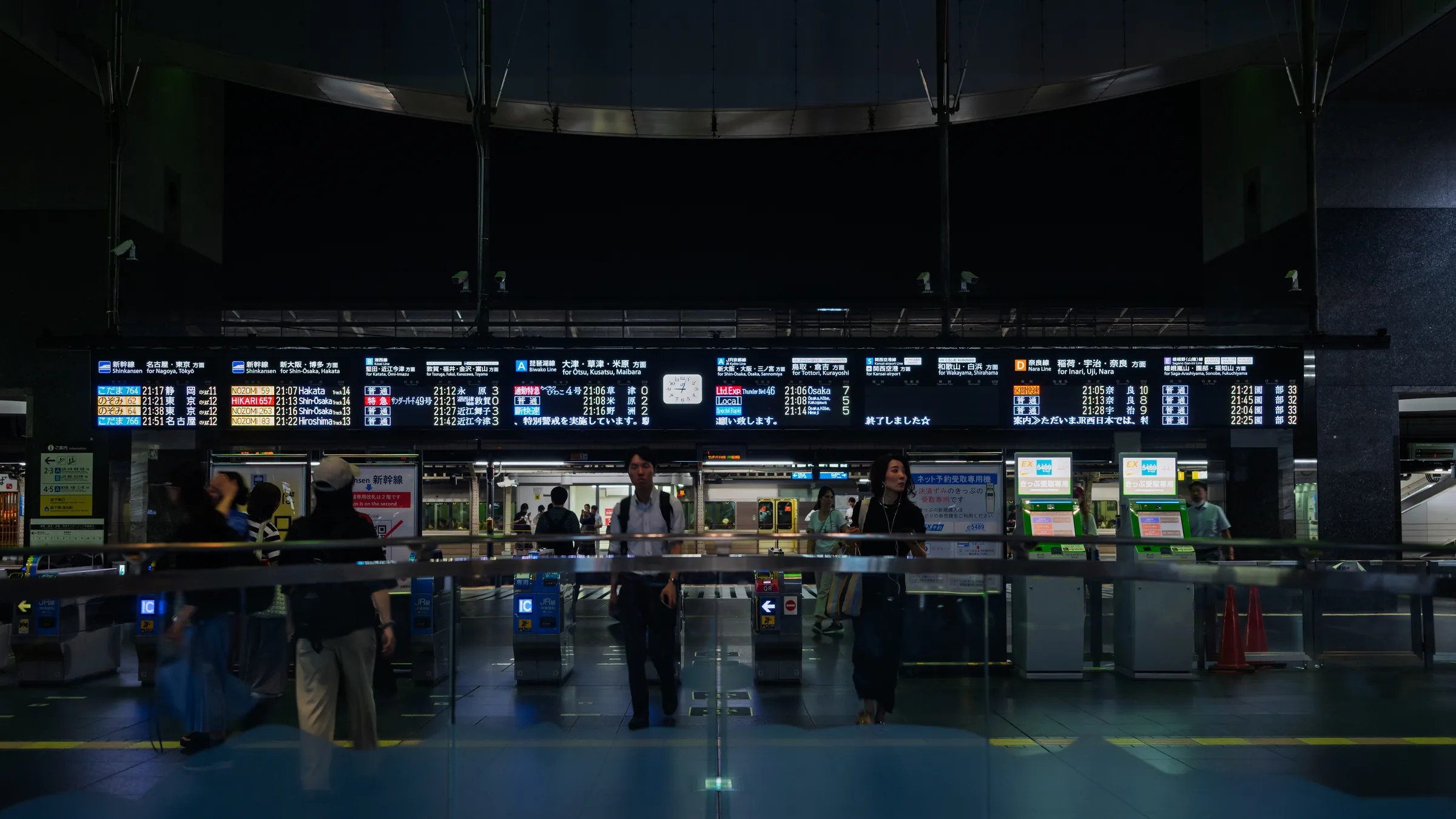 A dark Kyoto Station hall with ticket counters and scattered late-night travelers