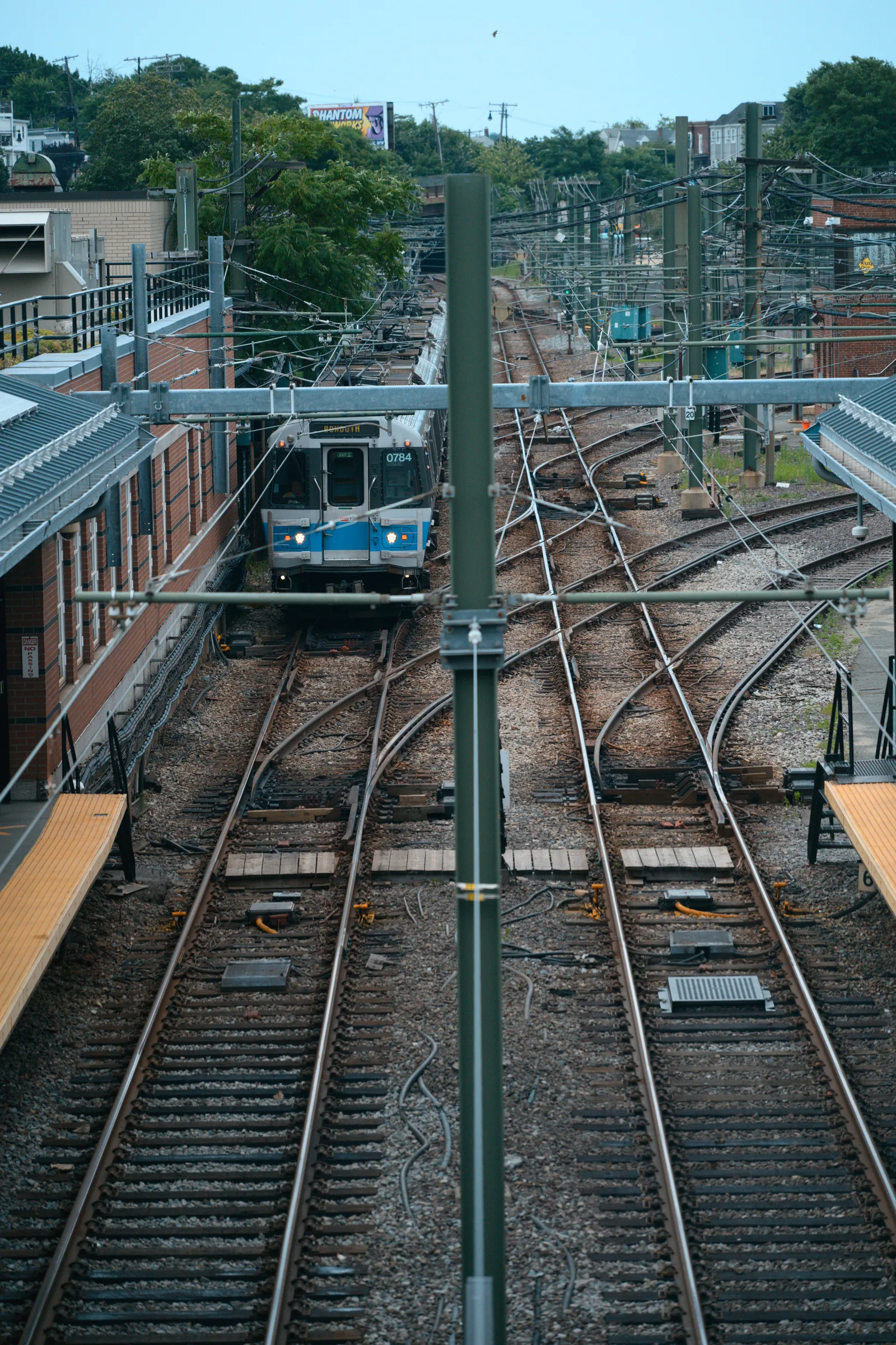 A blue-front train approaching through a rail yard where several tracks branch and cross
