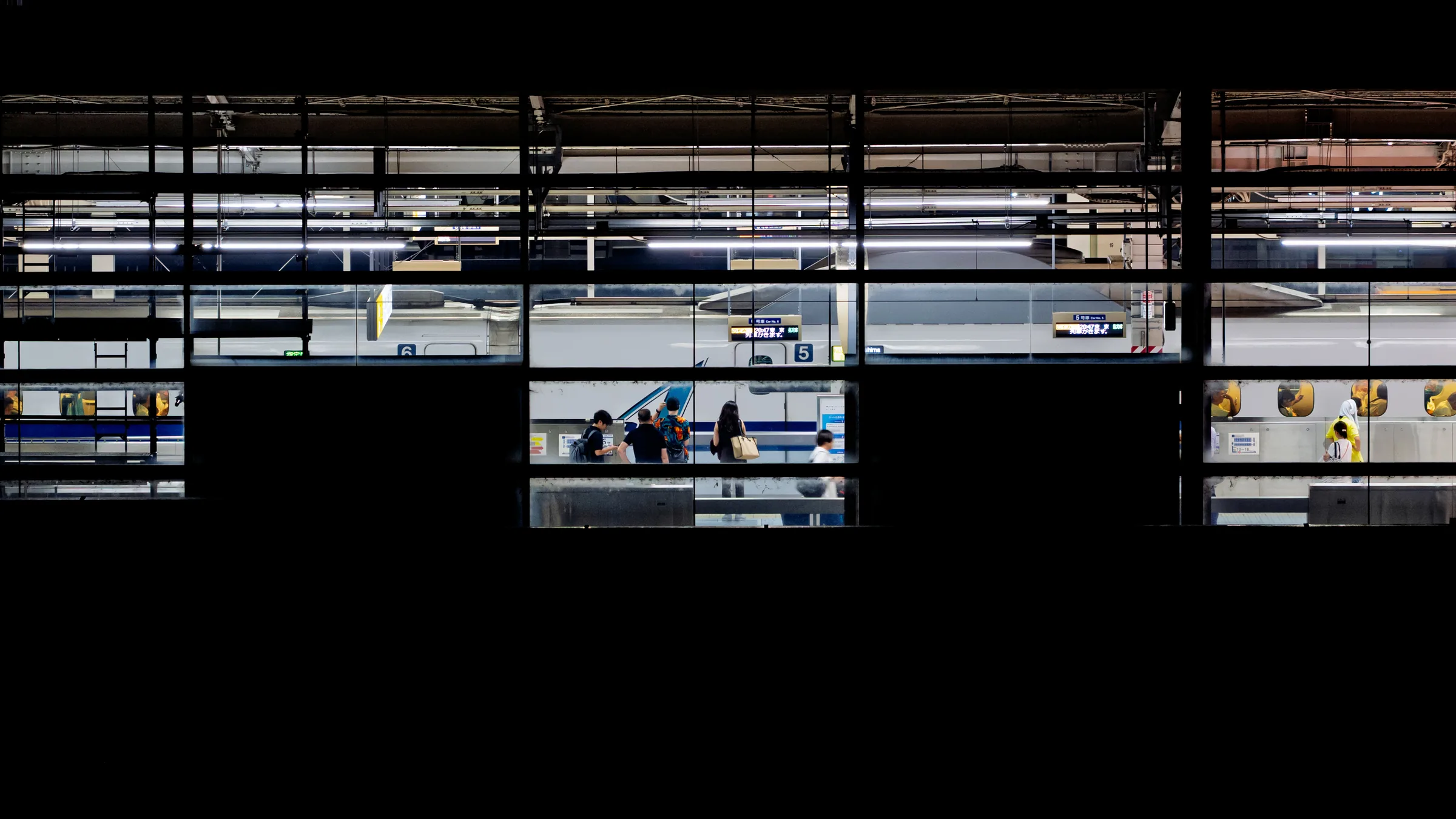 Bands of illuminated station platforms and small groups of travelers surrounded by darkness