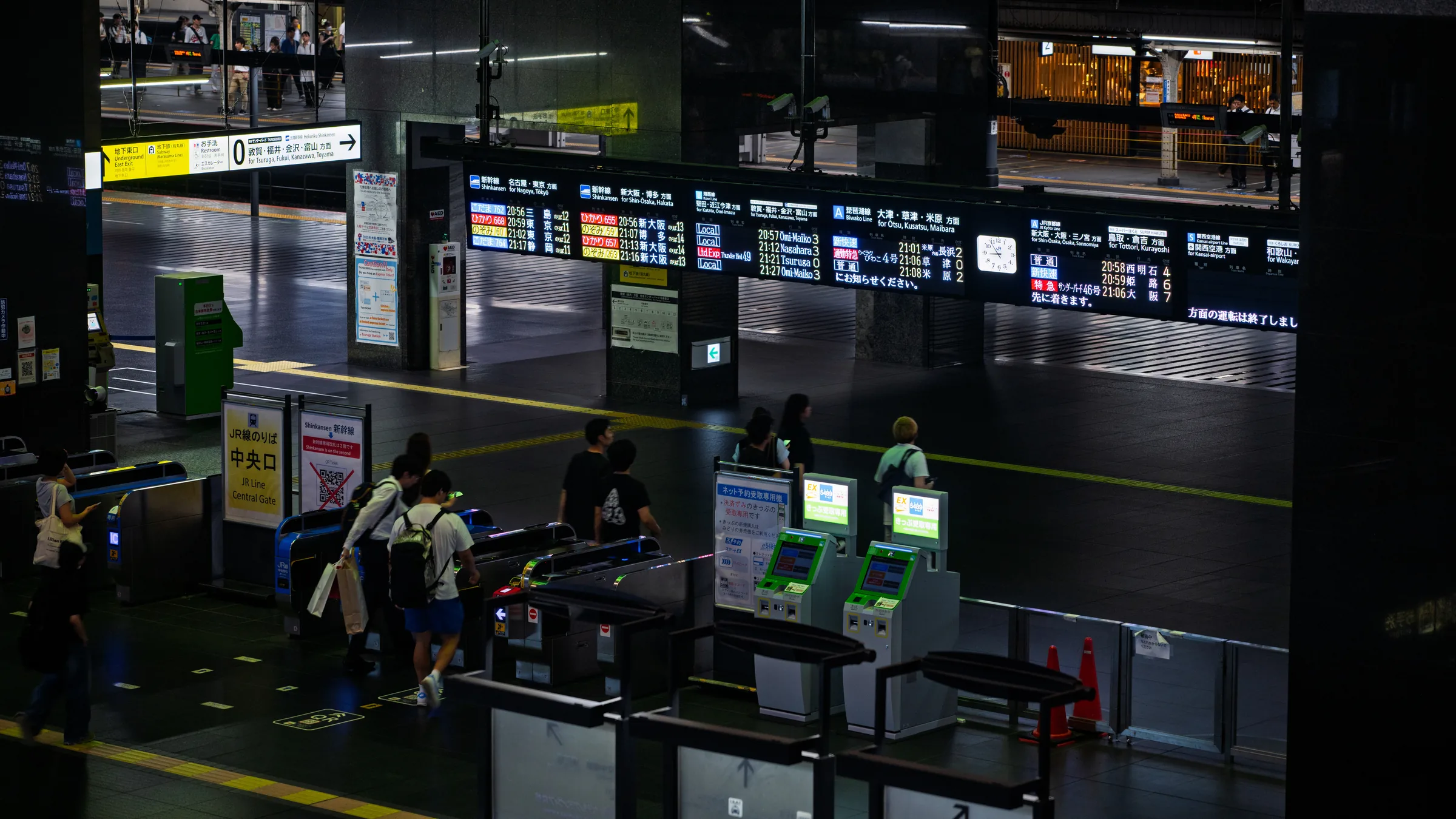 Travelers using ticket machines beneath signs and departure information at Kyoto Station