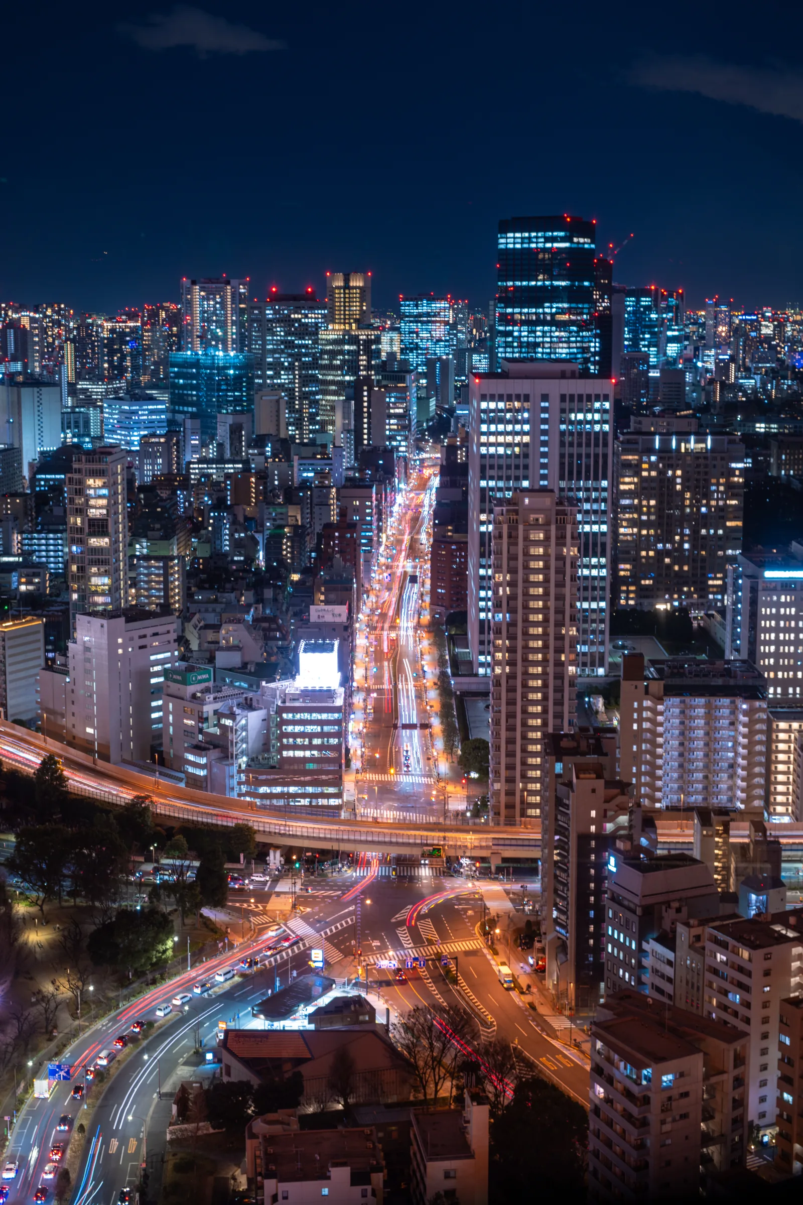 Night traffic drawing bright lines through a dense city of illuminated towers